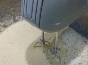 Handrührer beim Aufschlagen von Eiern, Milch und Mehl